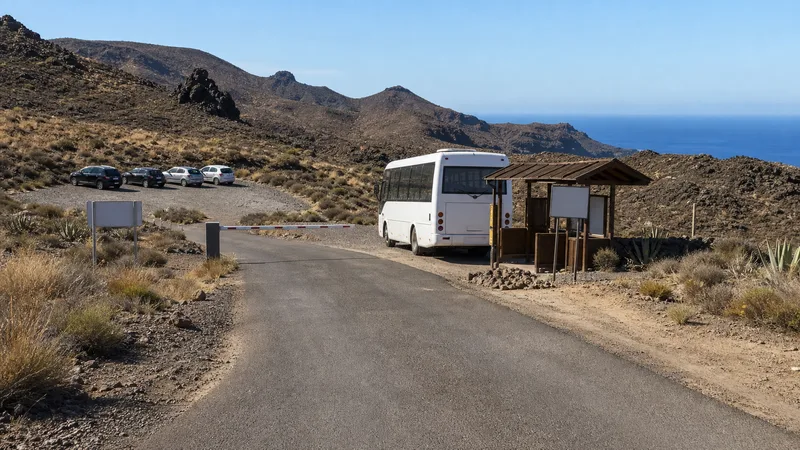 Barrera, autobús y aparcamiento en un acceso costero árido