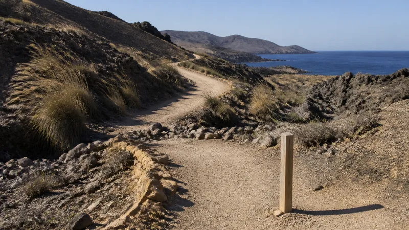 Sendero sin sombra entre rocas volcánicas y costa
