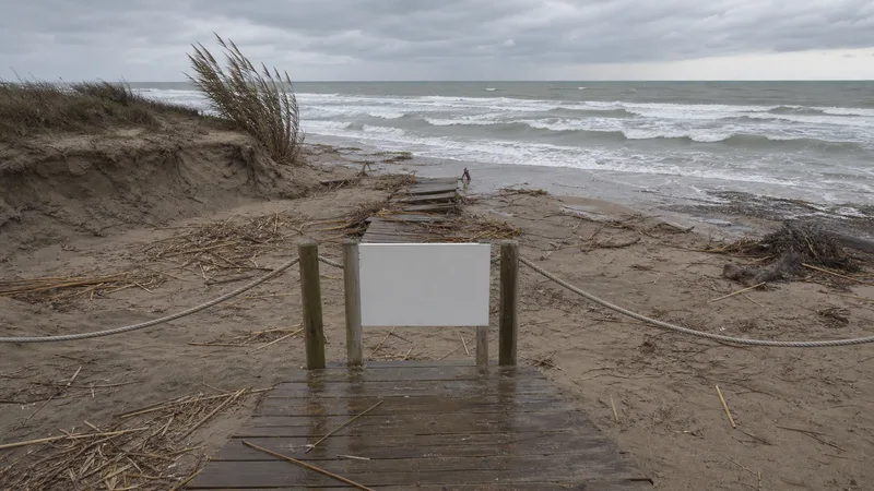 Pasarela cerrada ante una playa erosionada después de un temporal