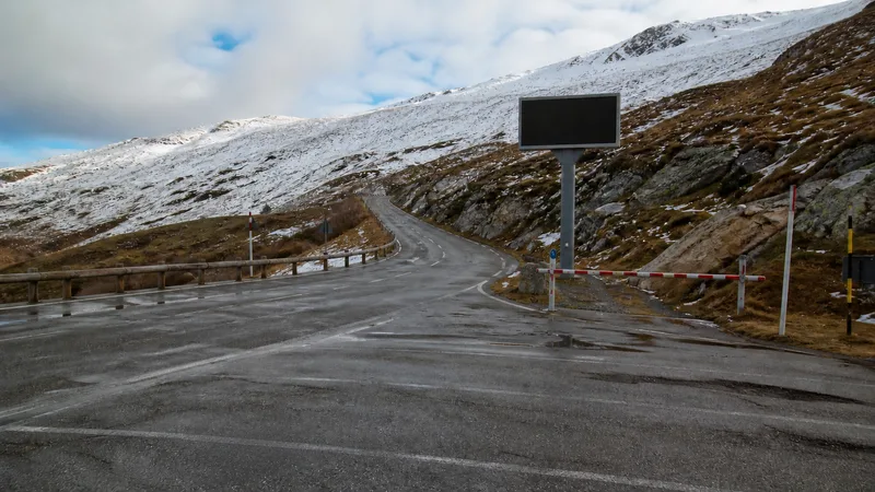 Carretera de sierra húmeda con nieve irregular, desvío cerrado y panel apagado