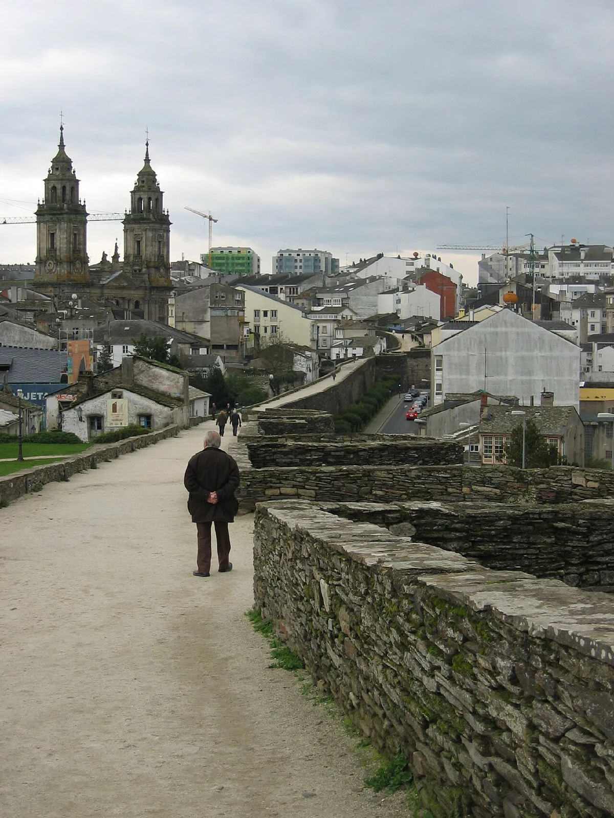 Paseantes sobre el adarve de la muralla de Lugo con vistas hacia la catedral