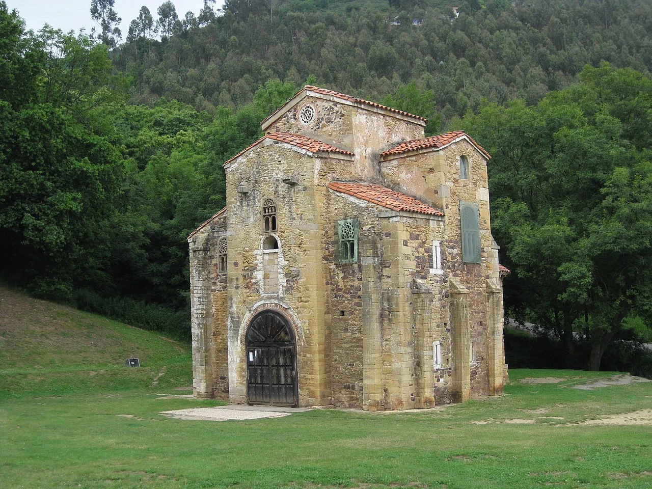 Exterior de San Miguel de Lillo junto al prado y la arboleda