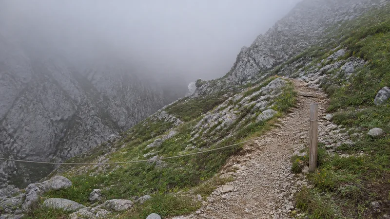 Sendero calizo húmedo mientras la niebla entra por un collado
