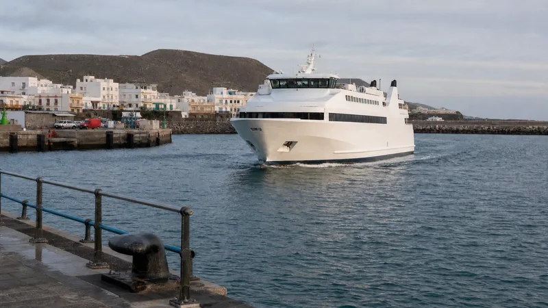 Ferri de pasajeros entrando en un puerto insular de casas blancas