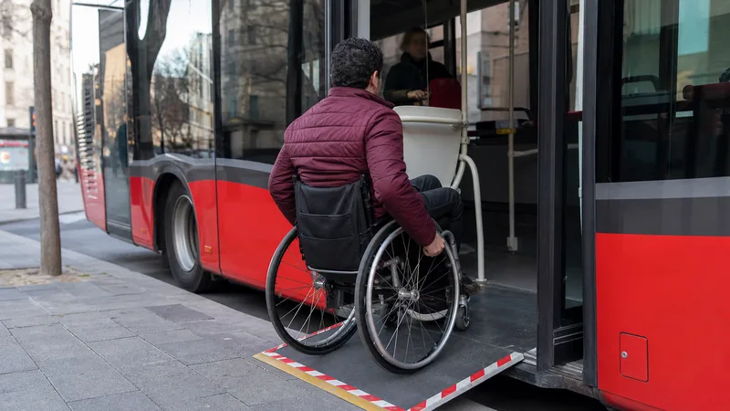 Persona usuaria de silla de ruedas subiendo a un autobús por la rampa