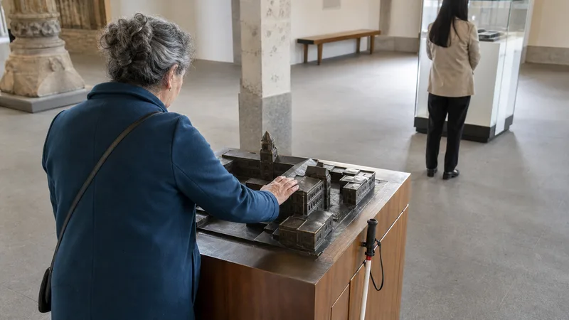 Visitante ciega explorando con las manos una maqueta arquitectónica