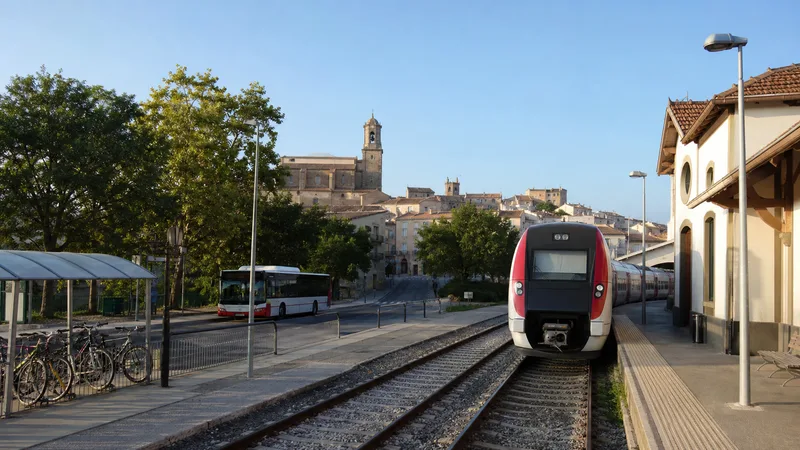 Estación regional con tren, autobús, bicicletas y casco urbano próximo