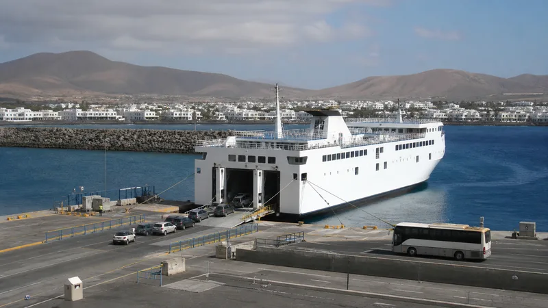 Ferry de vehículos y autobús en un puerto insular de paisaje volcánico