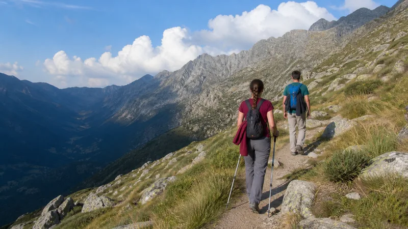 Dos senderistas avanzan por un camino de montaña mientras crecen nubes