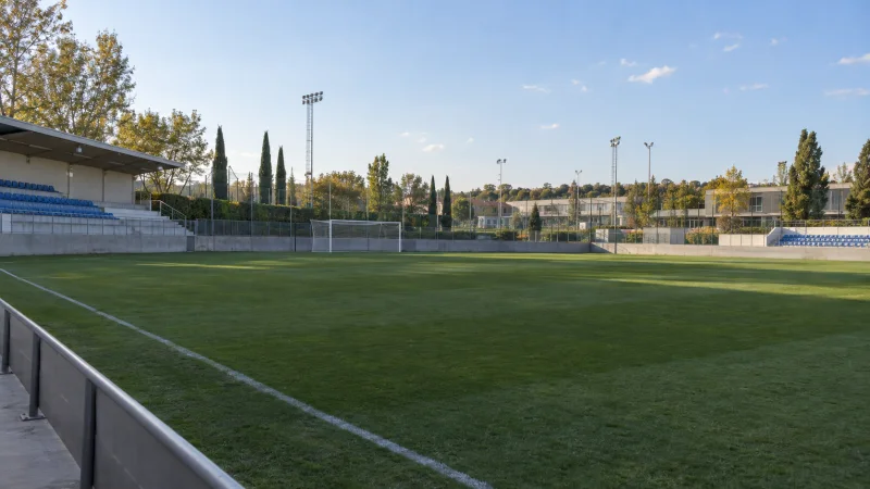 Campo de fútbol de un estadio madrileño al final de la tarde, con las gradas vacías.