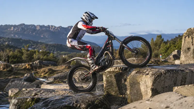 Piloto anónimo de trial supera un bloque de roca en un circuito al aire libre