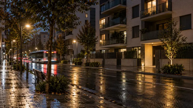Bloque residencial contemporáneo junto a una calle mojada por la lluvia durante la noche