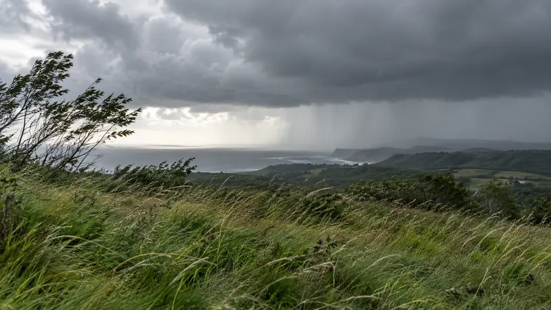 Nubes de un frente atlántico y cortinas de lluvia sobre una costa verde azotada por el viento